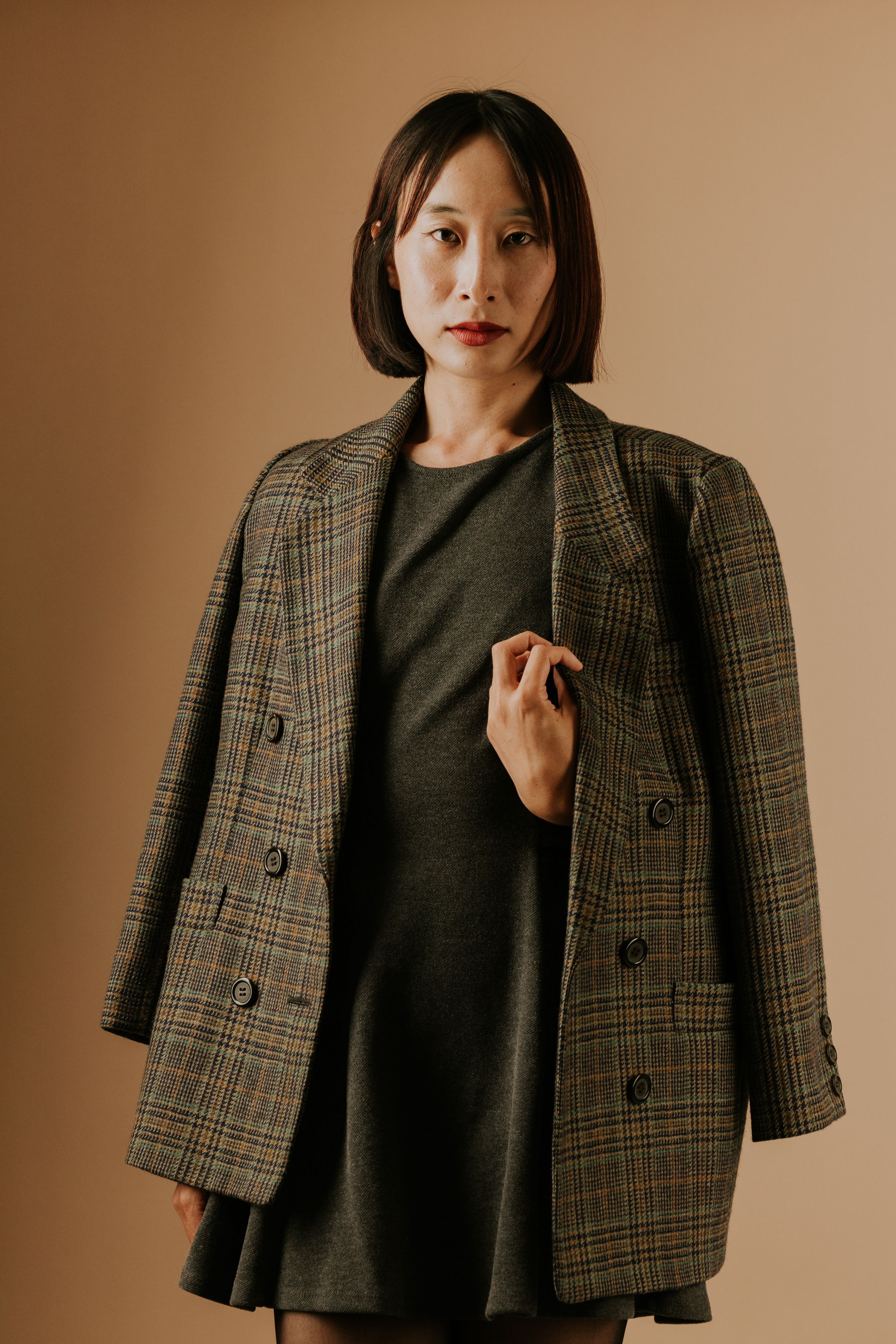 Portrait of a woman in a plaid jacket against a neutral background. Style and elegance.