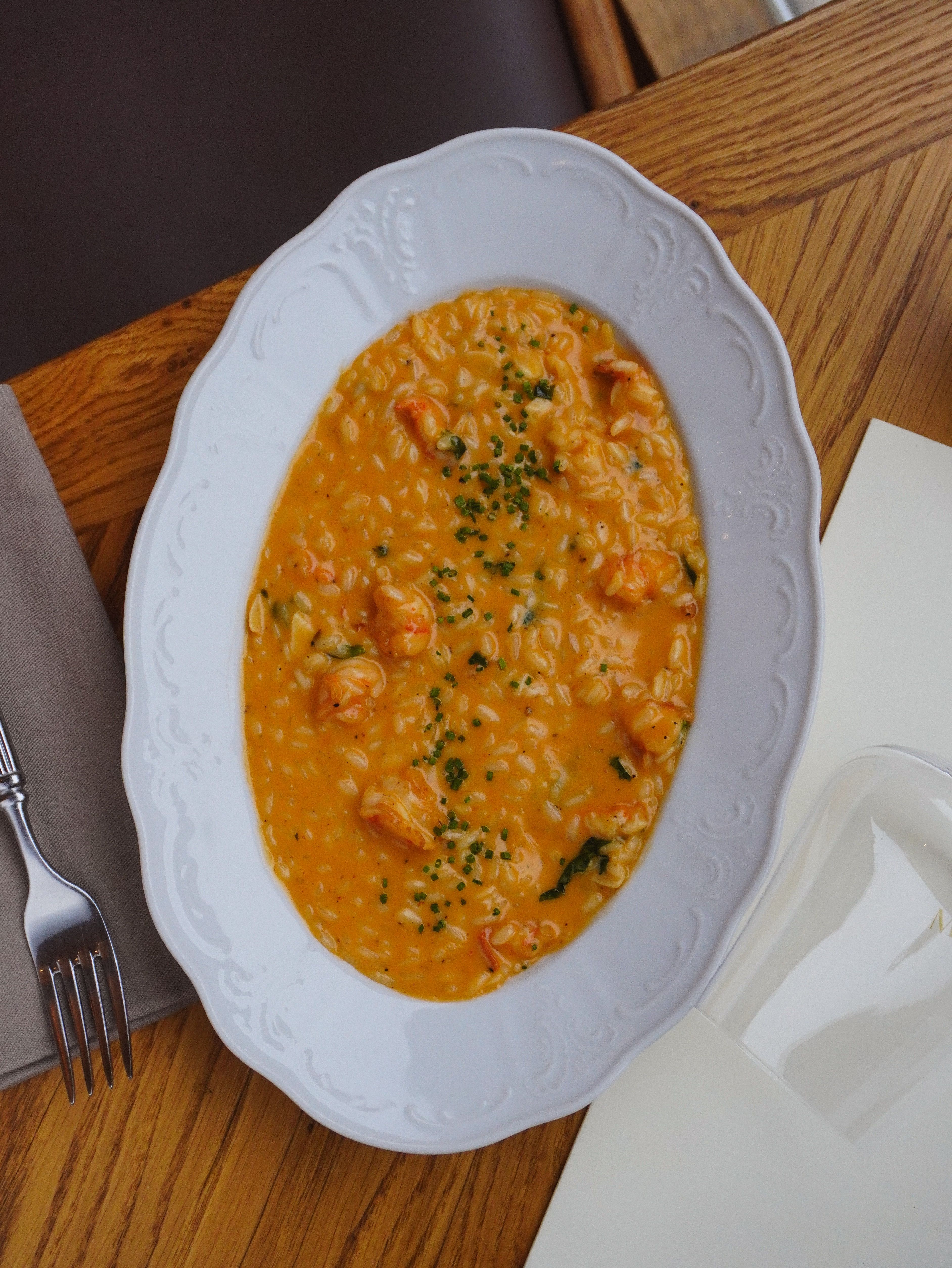 Close-up of a creamy lobster risotto on a white plate with parsley garnish.