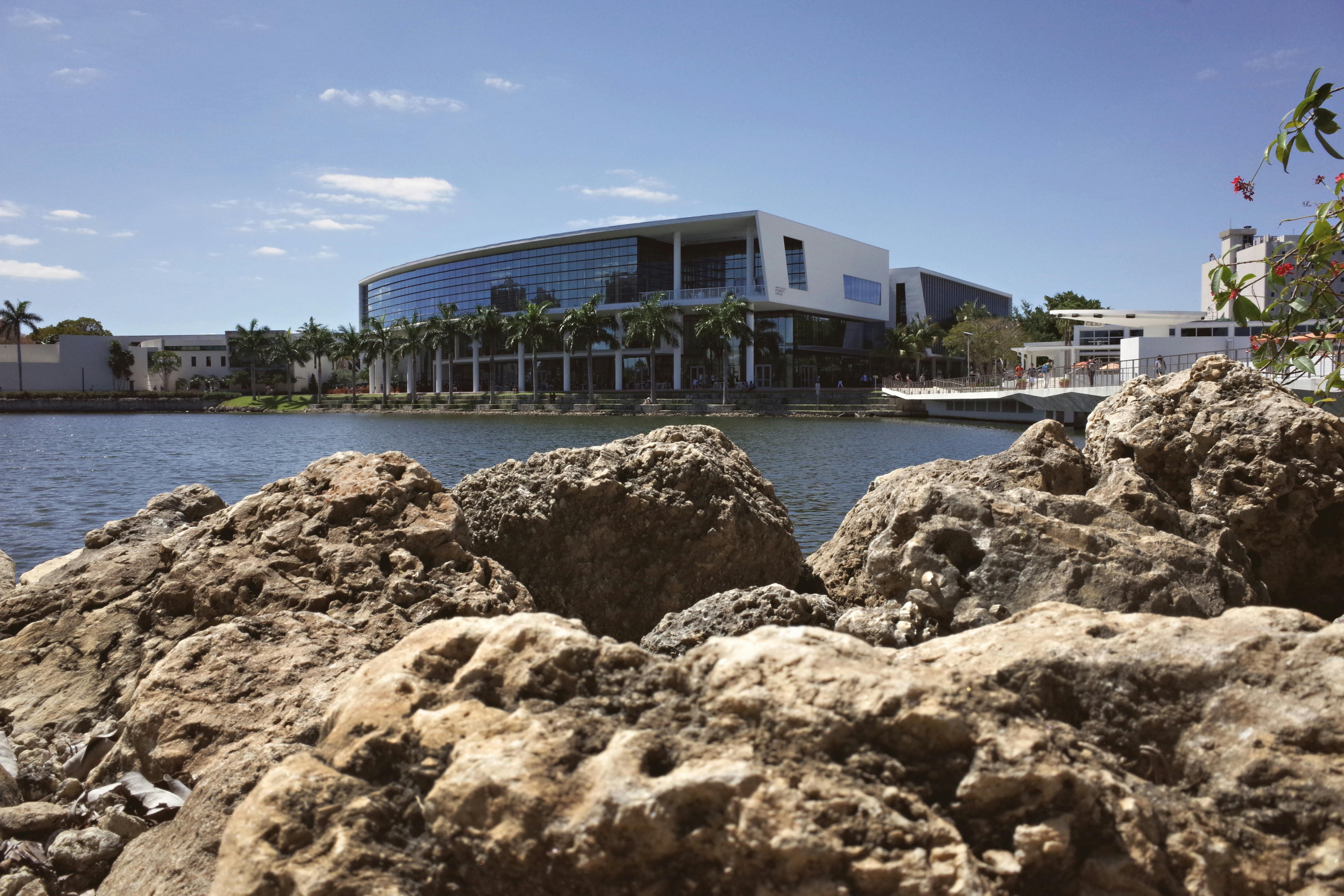 View of a modern university campus in Coral Gables, Florida with waterfront and rocks.
