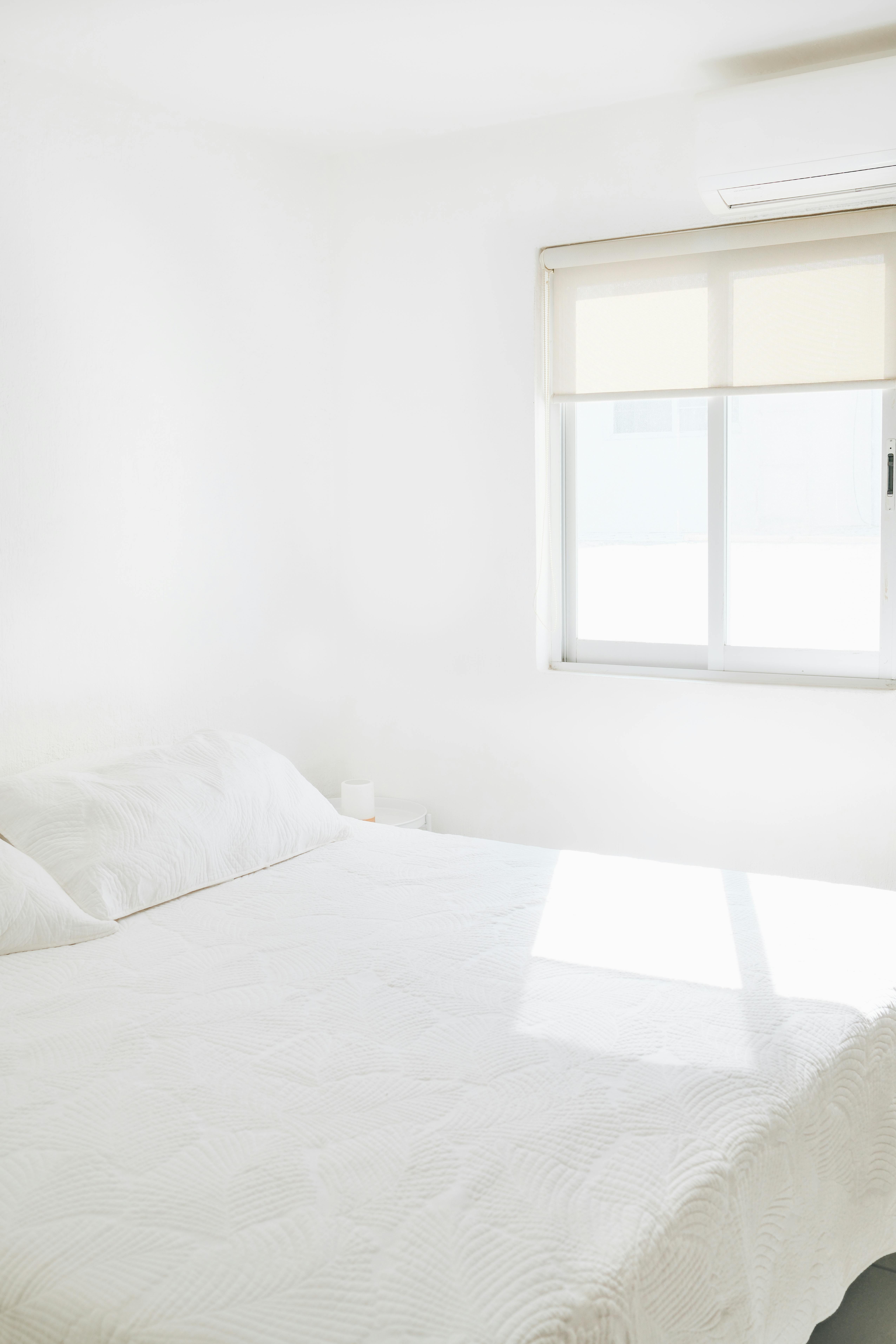 Simple and elegant minimalist bedroom with natural light from a window.