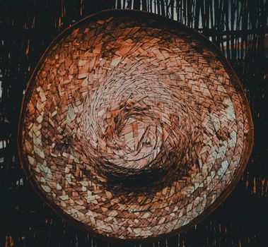Detailed photograph of a traditional woven straw hat against a wooden background.