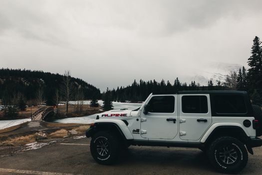 White Jeep parked in scenic Banff, Canada, surrounded by nature's beauty.