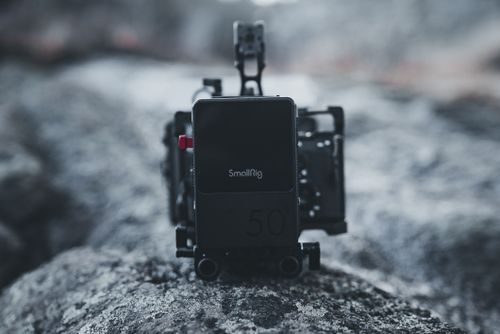 Free A cinematic close-up of a SmallRig camera setup placed on a rocky surface, showcasing professional filming gear. Stock Photo