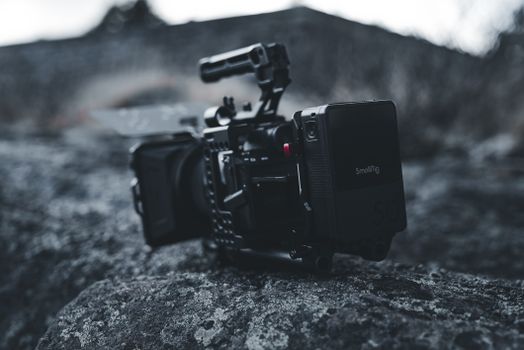 Close-up of a professional video camera rig on rocky outdoor terrain, showcasing high-end filming gear.