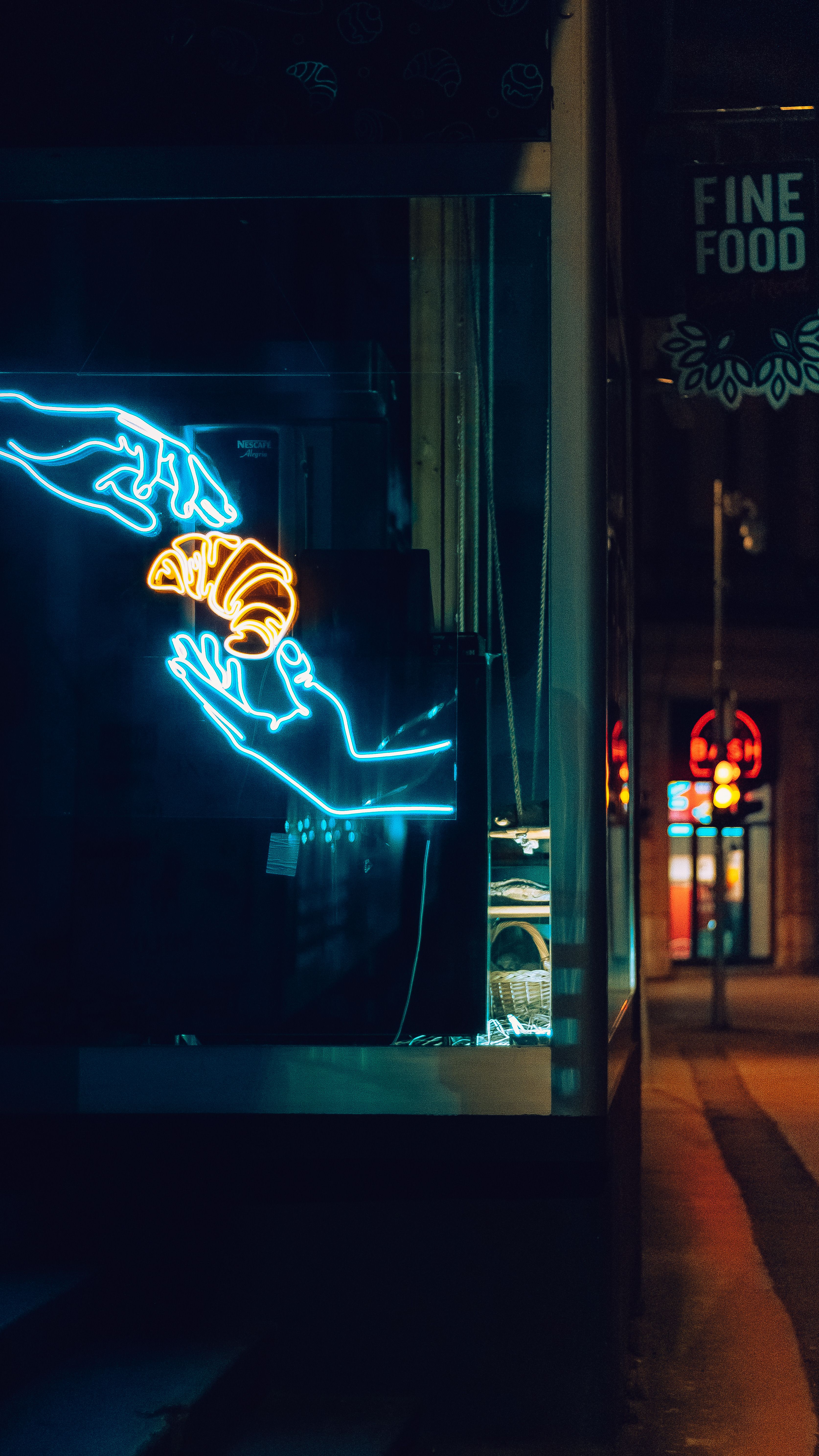 Vibrant neon art depicting hands exchanging a croissant in a city nightscape.
