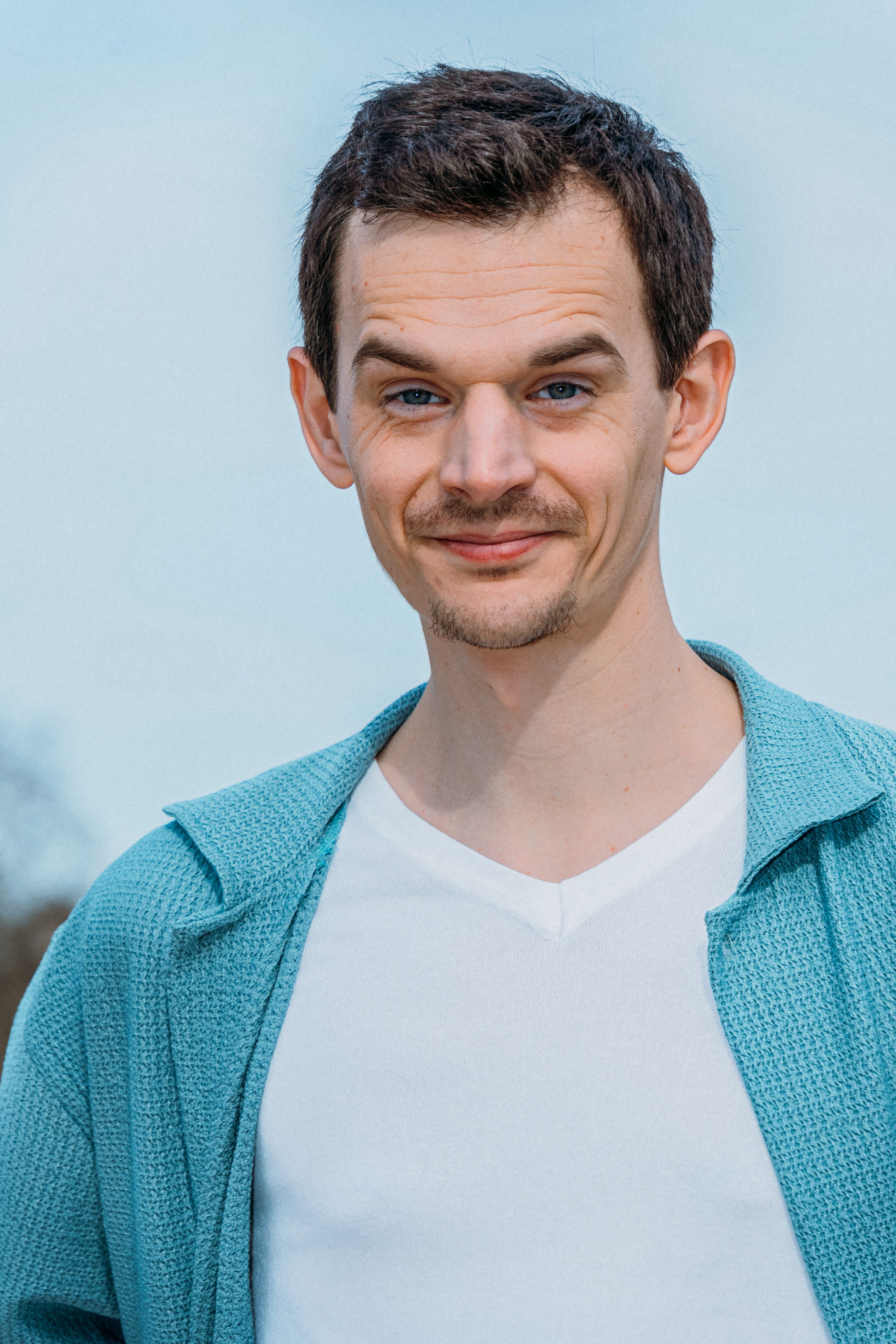 Smiling man in casual attire outdoors in Paris, embodying modern style and confidence.