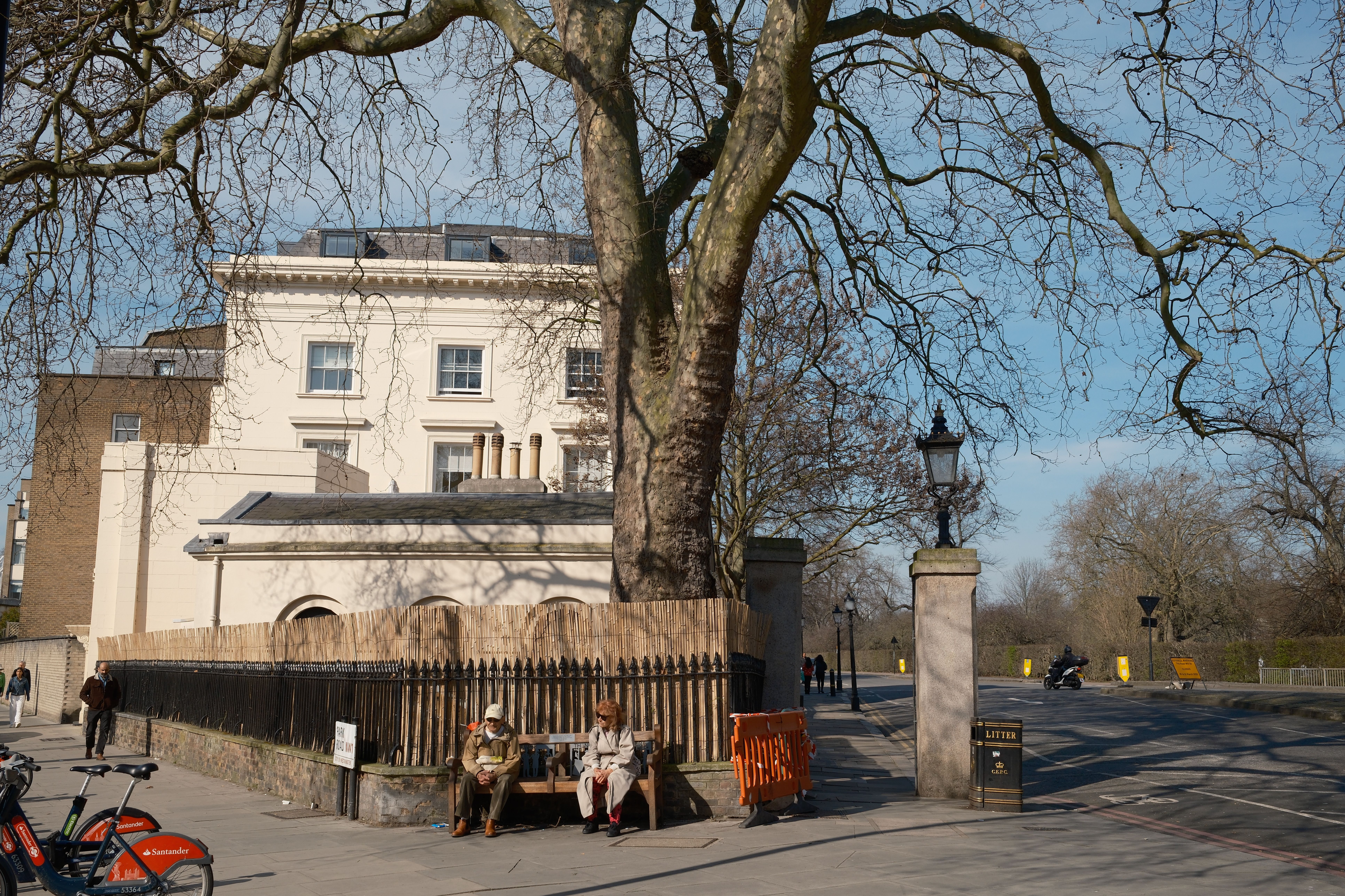 Charming urban scene with people relaxing by historical building and tree-lined street.