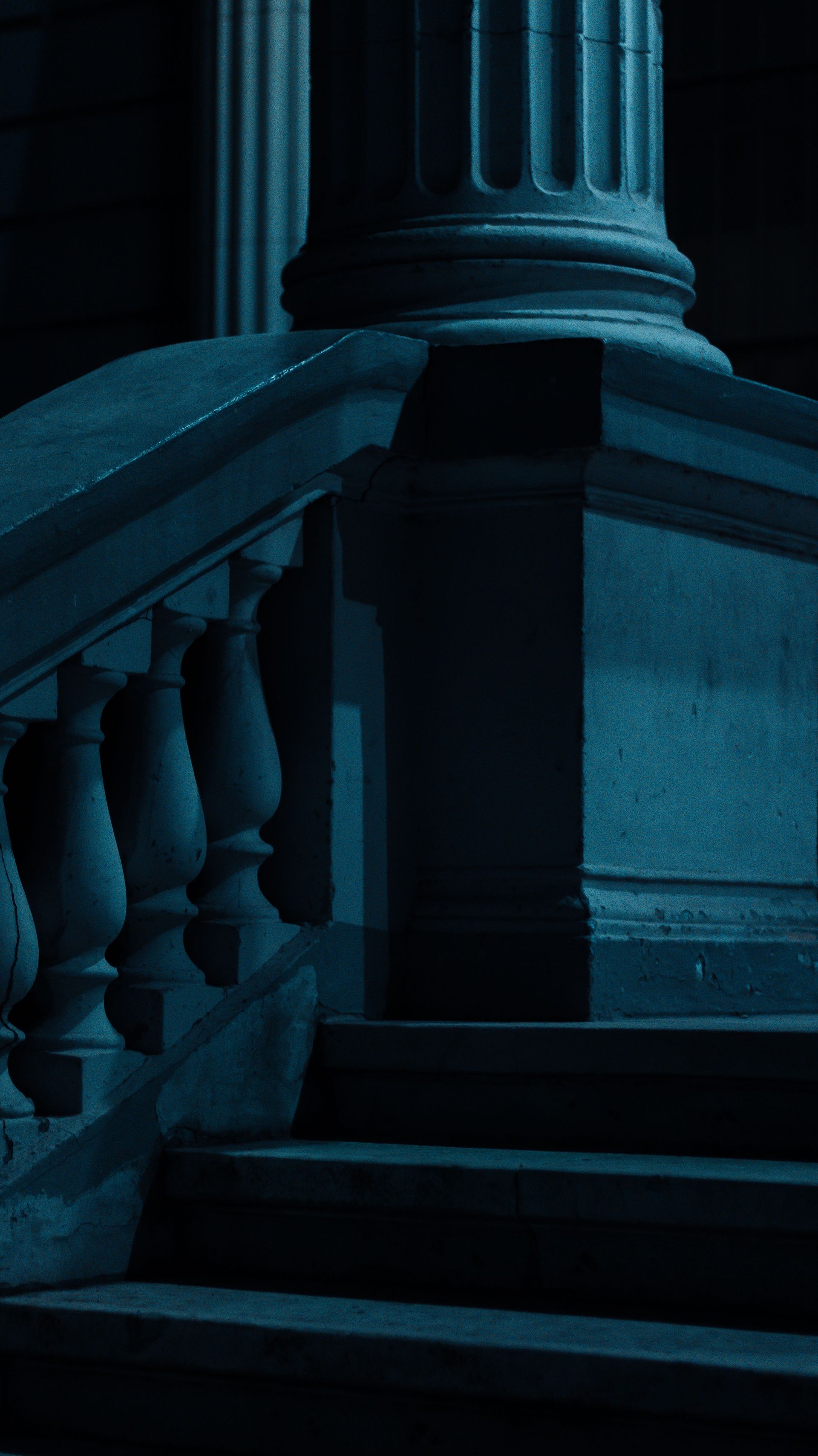 Moody night photograph of classical column architecture with dark blue lighting