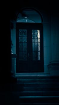 A mysterious and dimly lit entrance with a dark wooden door surrounded by architectural columns.