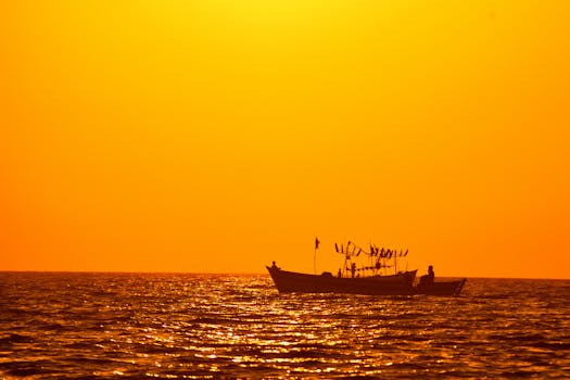 A boat silhouetted against a radiant orange sunset over the Arabian Sea from Dwarka, India.