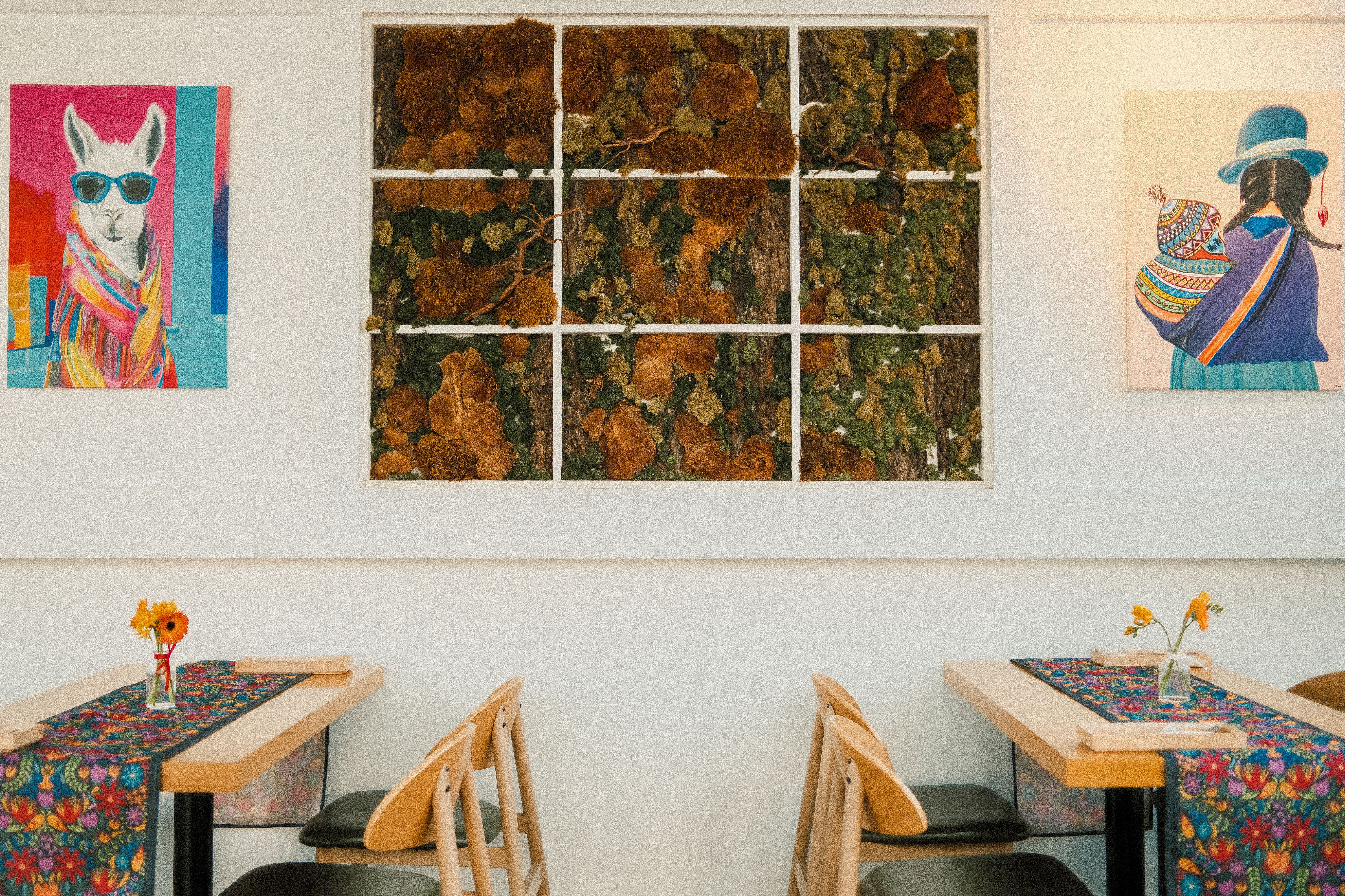 Bright cafeteria interior with vibrant paintings and floral decor on tables