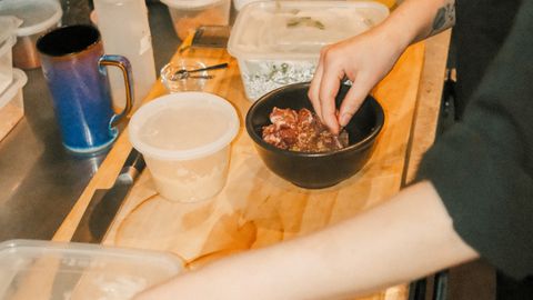 A chef arranging ingredients for a meal in a busy restaurant kitchen.