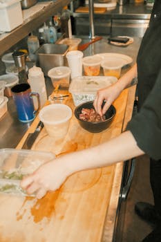 A chef arranging ingredients for a meal in a busy restaurant kitchen.