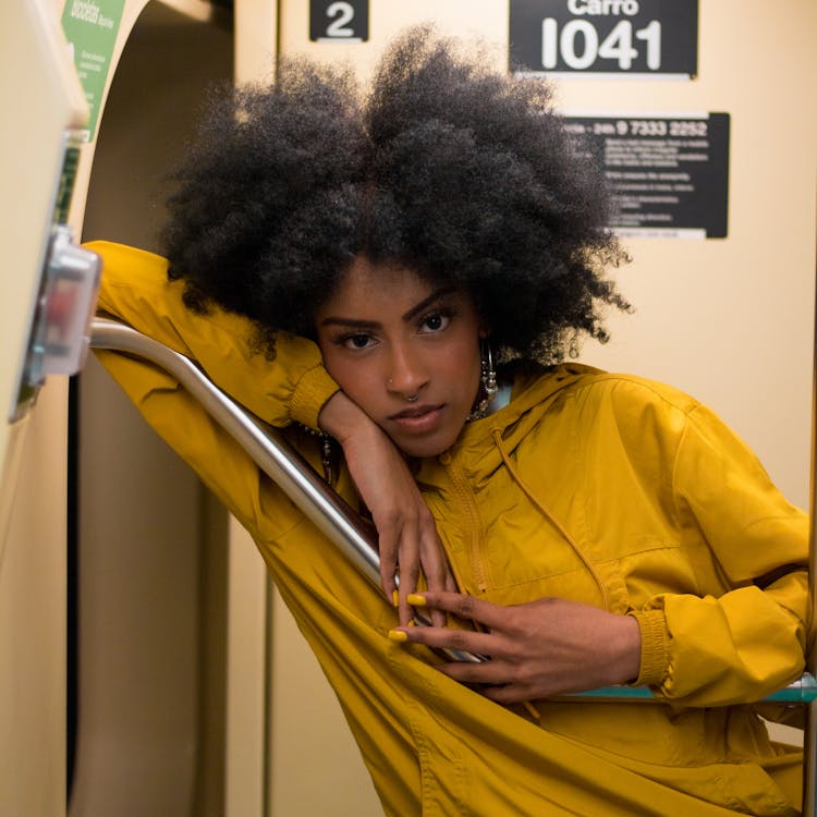 Woman Wearing Yellow Jacket Leaning On Metal Bar