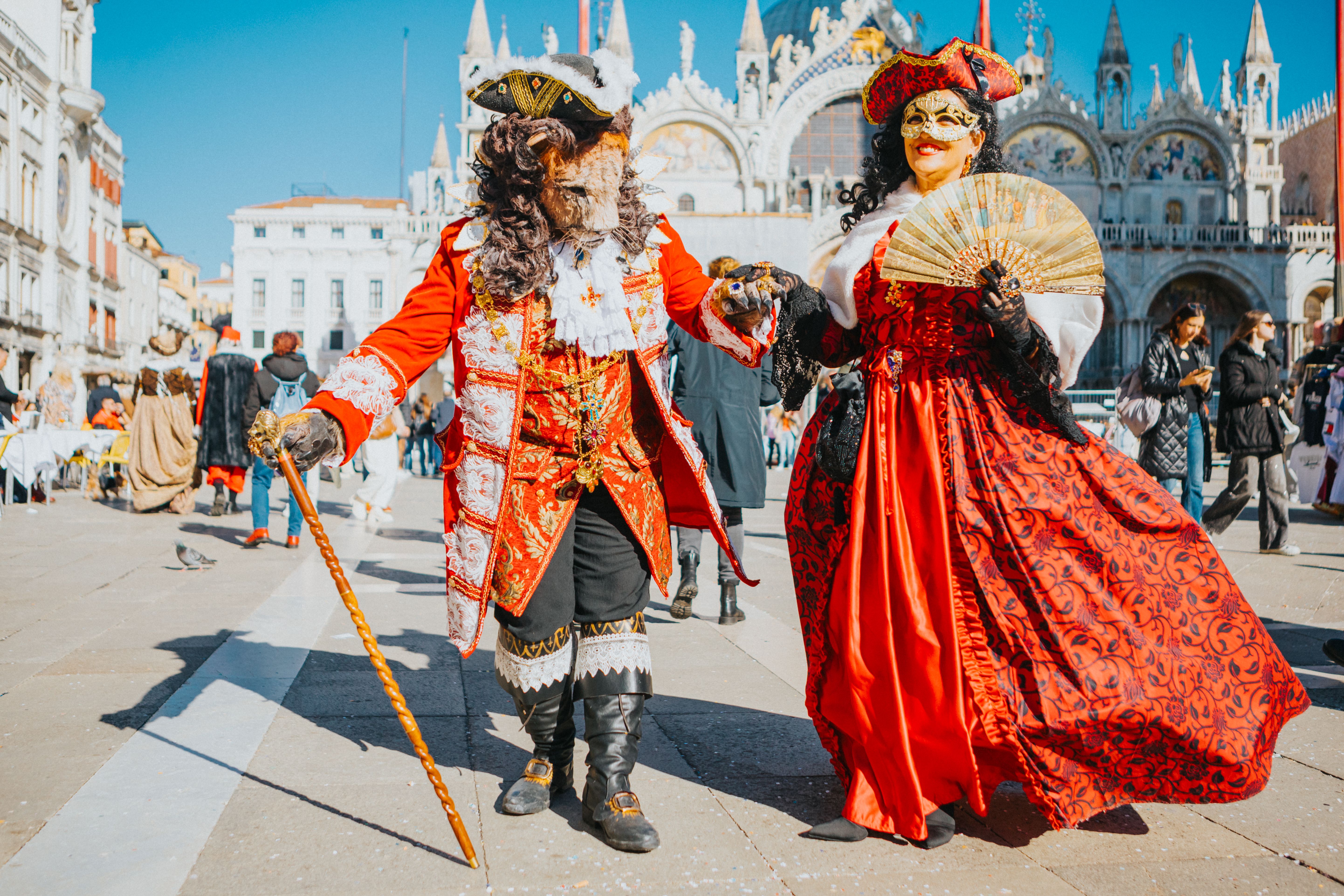 Colorful Venice Carnival costumes in St. Mark's Square, showcasing historical attire and vibrant masks.