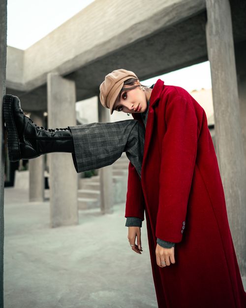 Free Fashion portrait of a person in a vivid red coat striking a bold pose outdoors. Stock Photo