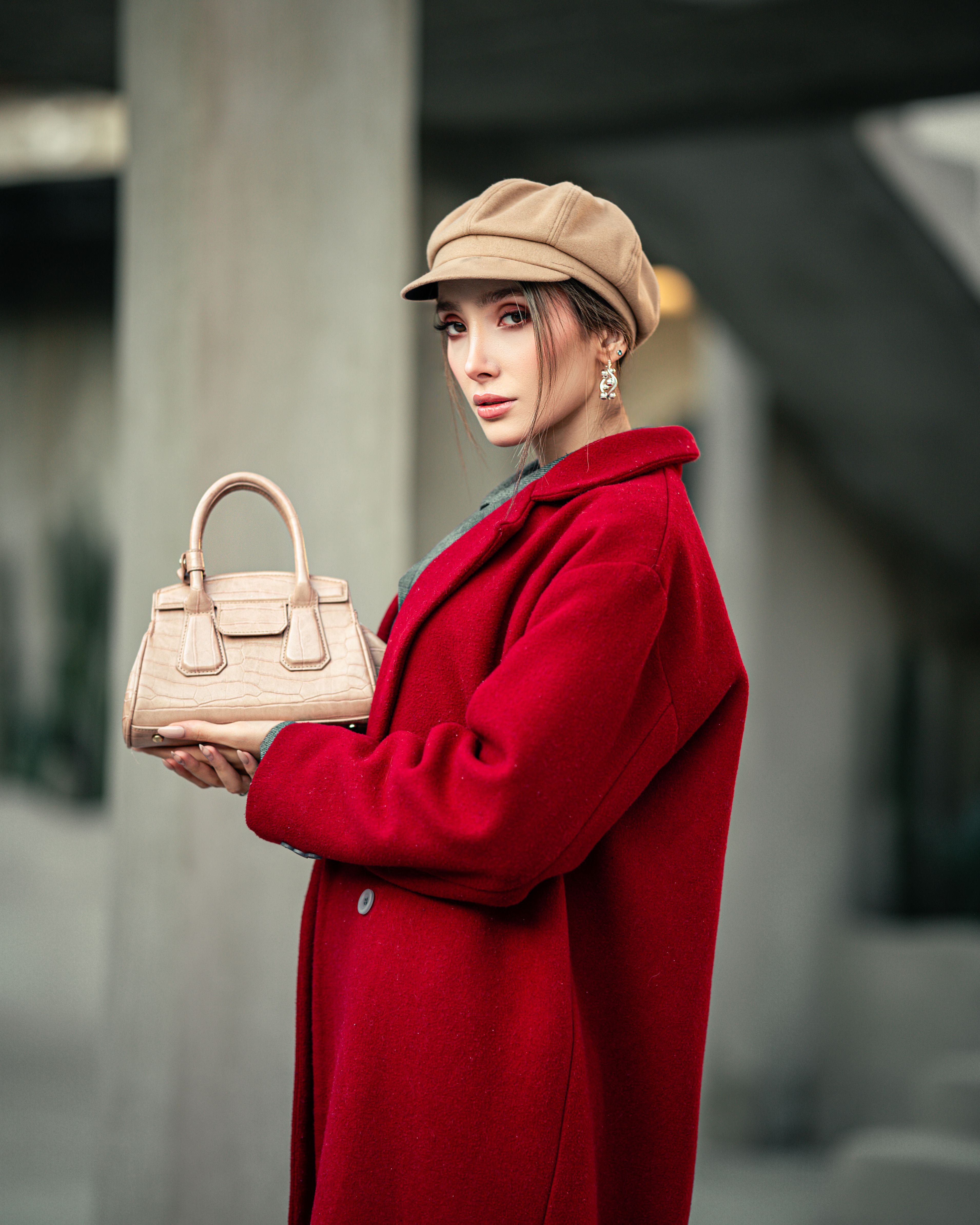 Chic woman in red coat and beige hat poses with handbag outdoors. - Assuming All Images Accurately Represent the Product