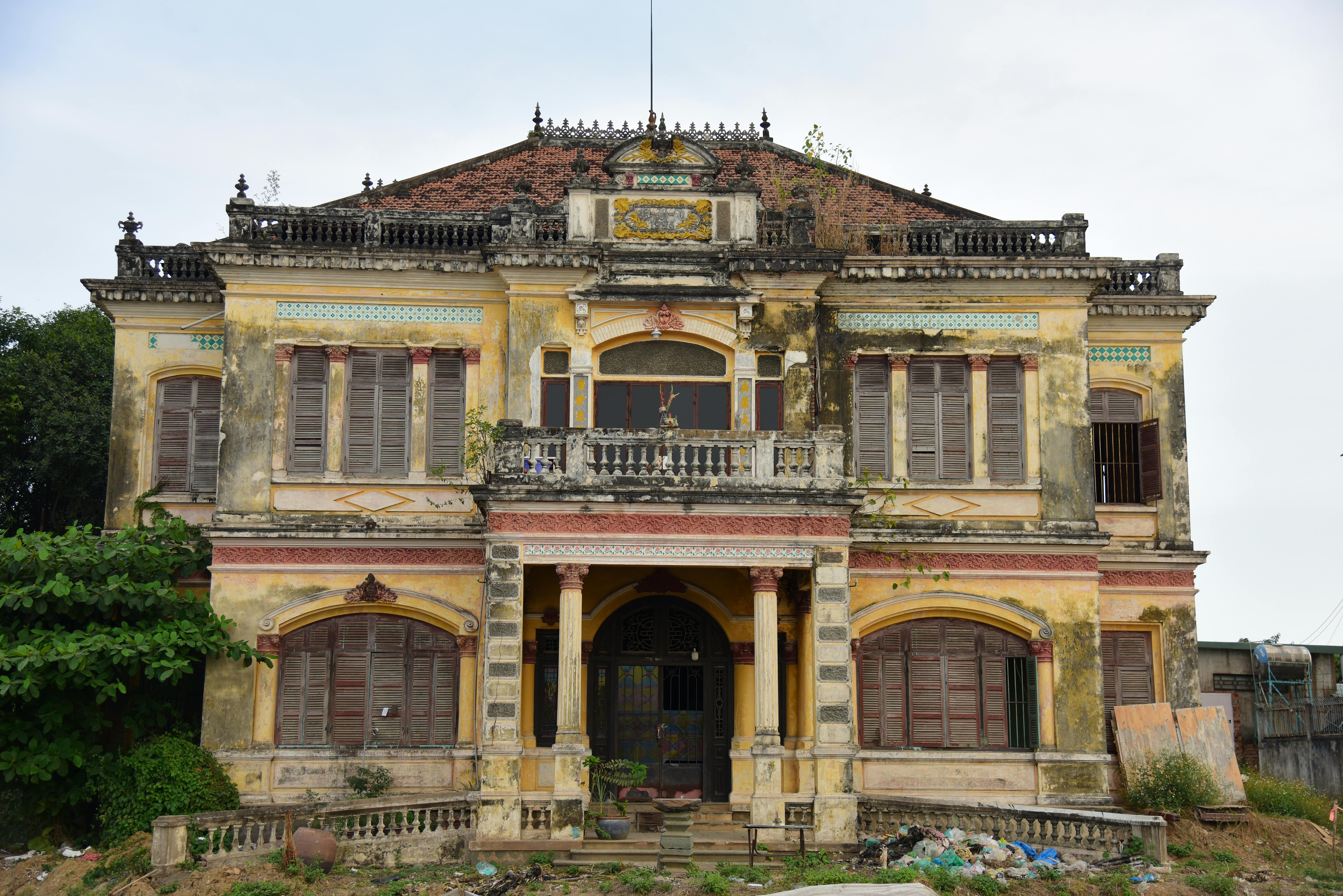 Aged colonial mansion with a weathered facade and overgrown vegetation adds an eerie charm.