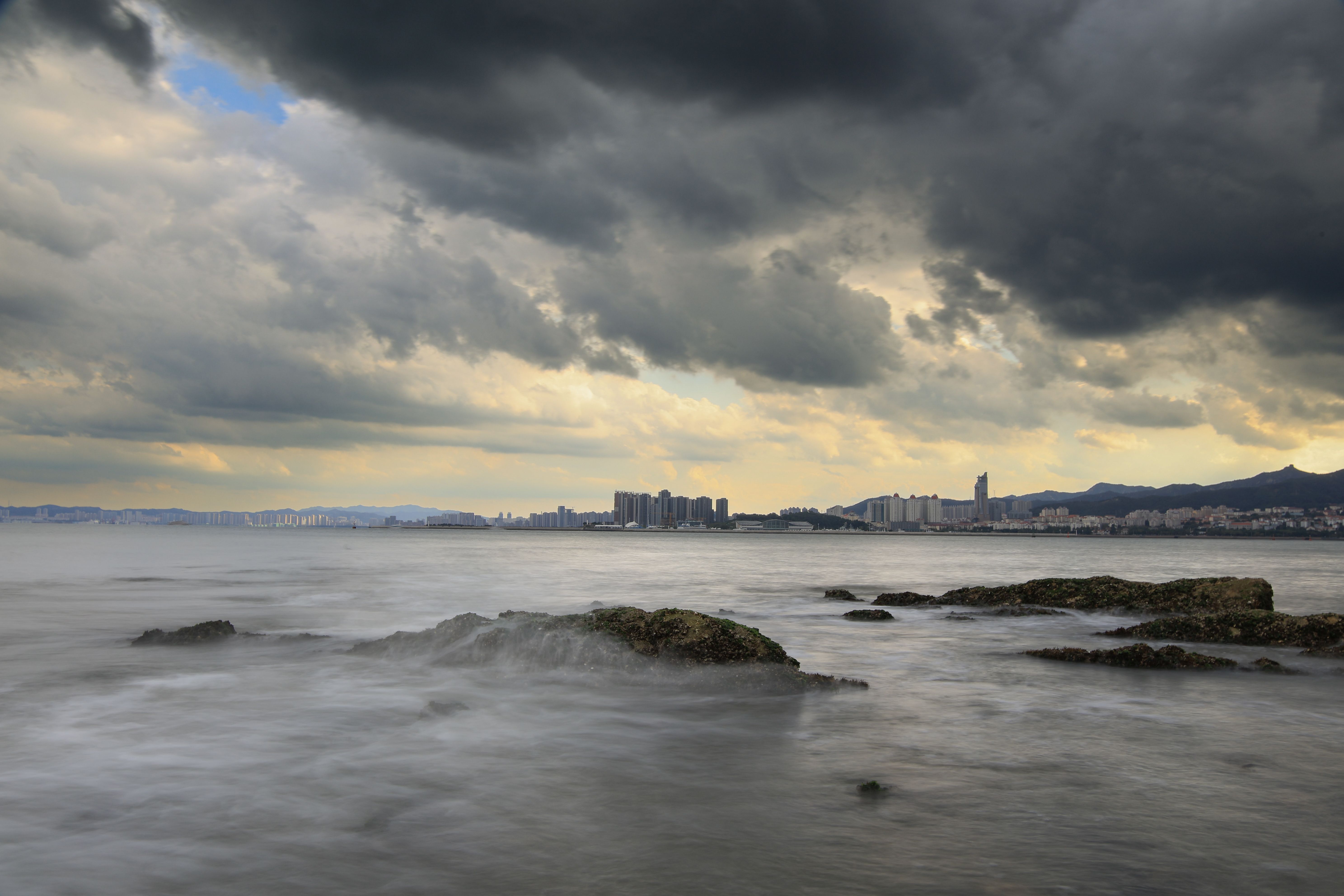 Dark storm clouds over a coastal city skyline