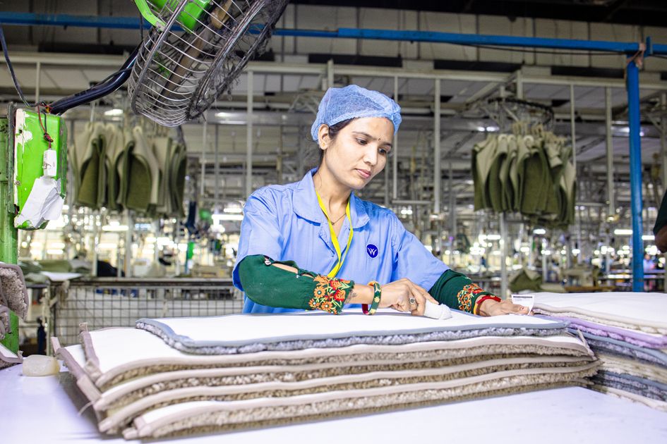 Công nhân kiểm tra các lớp vải dưới ánh sáng mạnh trong xưởng dệt may