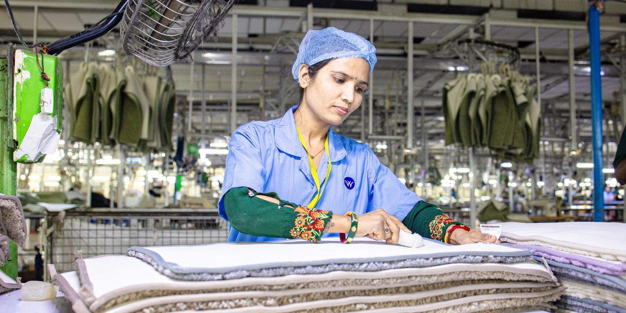 Công nhân kiểm tra các lớp vải dưới ánh sáng mạnh trong xưởng dệt may