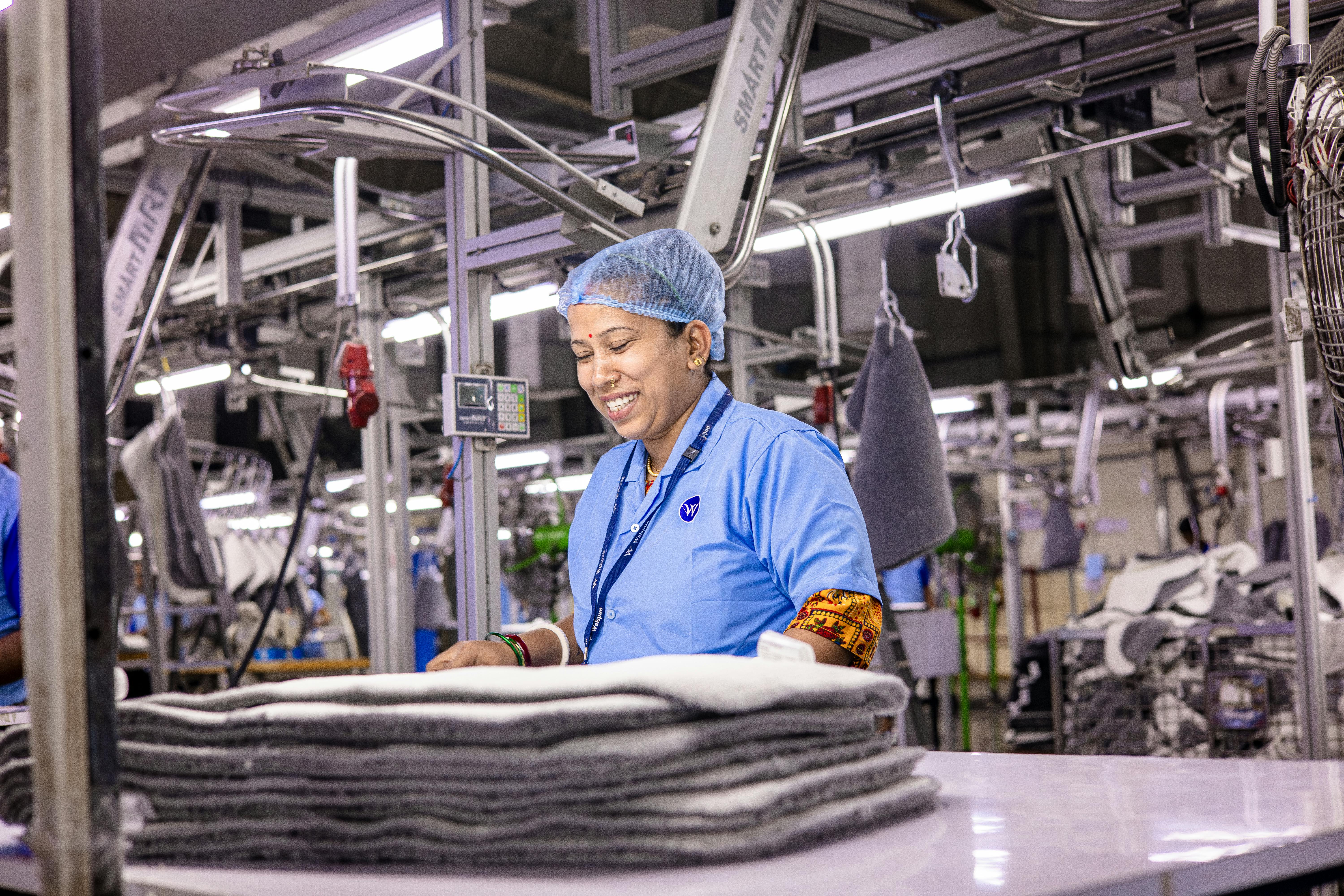 A textile factory worker wearing traditional attire smiling while working.