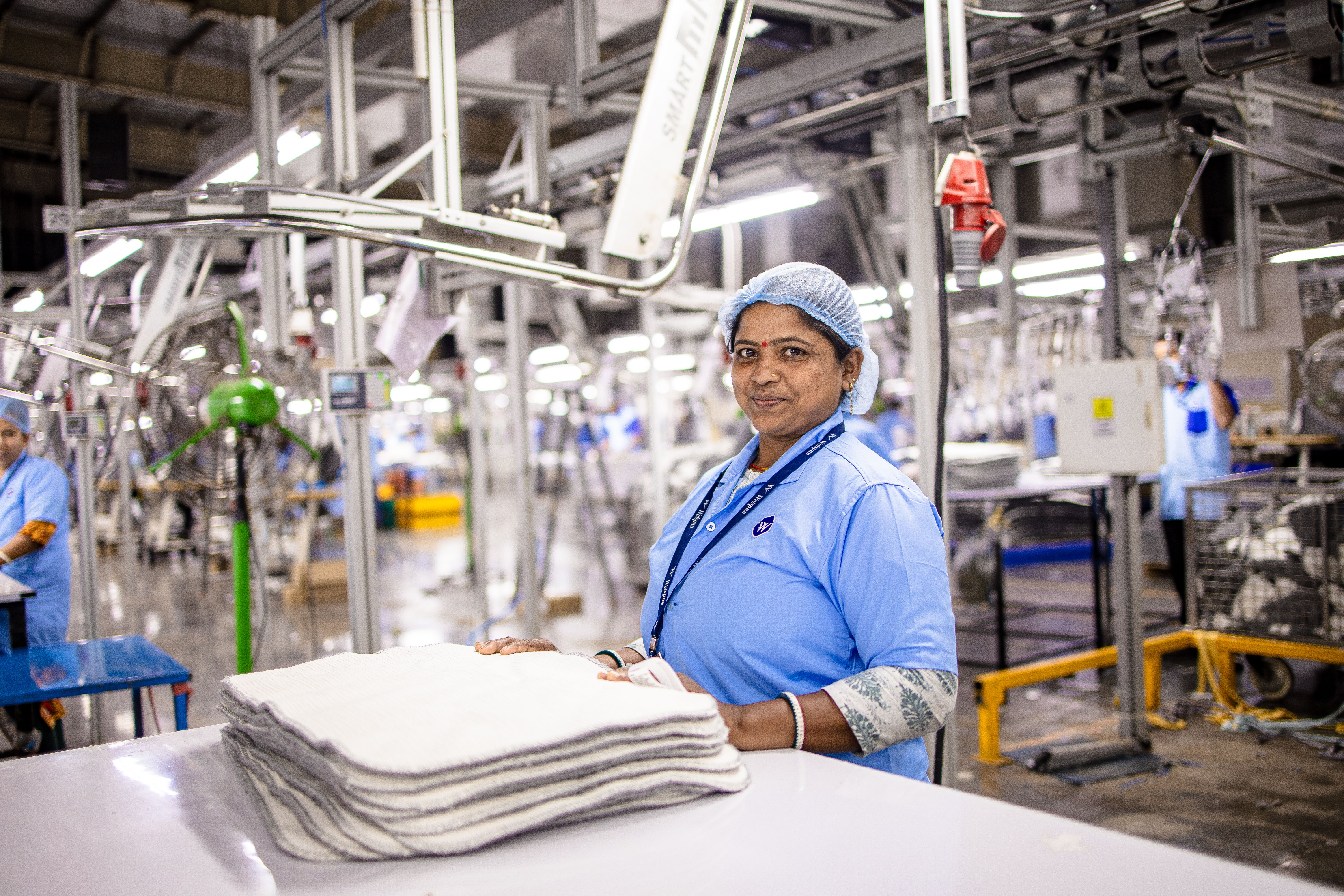 Female textile worker handling fabric in modern factory environment.