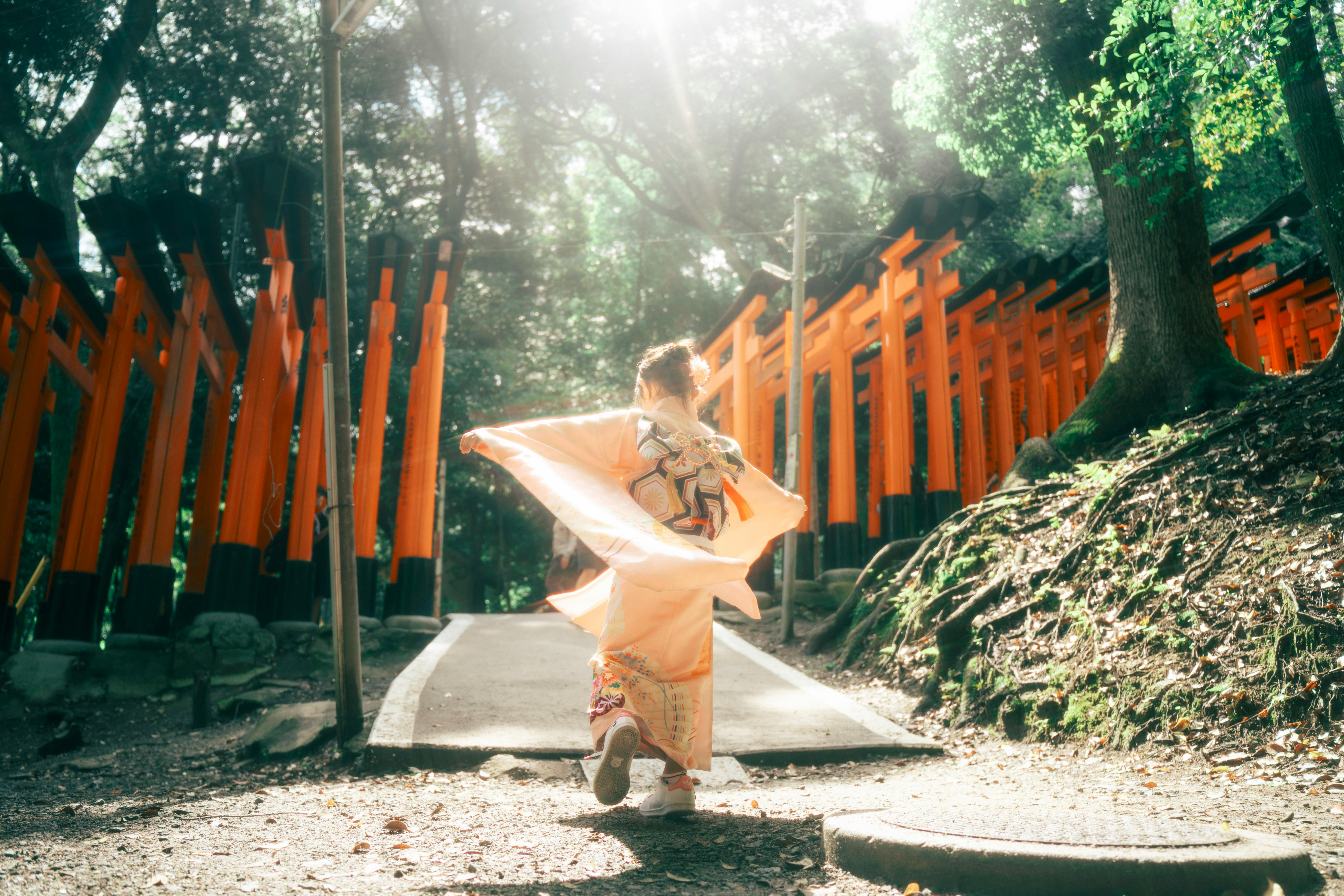 A woman in a kimono dances among the red torii gates at Fushimi Inari Shrine, Kyoto.
