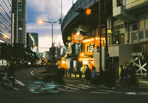 Bustling nightlife in Tokyo with illuminated signs and blurred motion of people.
