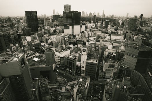 Dramatic black and white aerial view of Tokyo's urban landscape, showcasing iconic architecture and bustling city life.