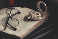 一本打开的书上放着一块老式怀表和一副眼镜，展现了一个经典的文学主题