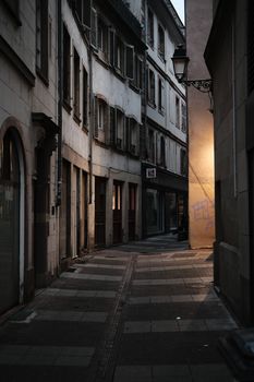 Atmospheric alleyway in a European city with warm lighting at dusk, exuding historic charm.
