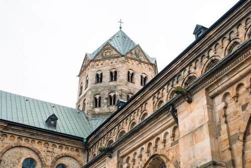 Free Close-up of a Romanesque cathedral tower with intricate stonework and a cross on top. Stock Photo
