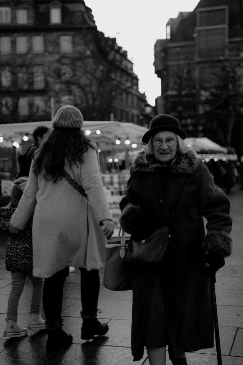 Free Elderly woman in winter coat walking through a street market. Stock Photo