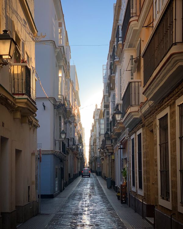Gratis Esplora l'affascinante stradina di Cadice, in Spagna, con la sua architettura storica e le tonalità dorate del tramonto. Foto a disposizione