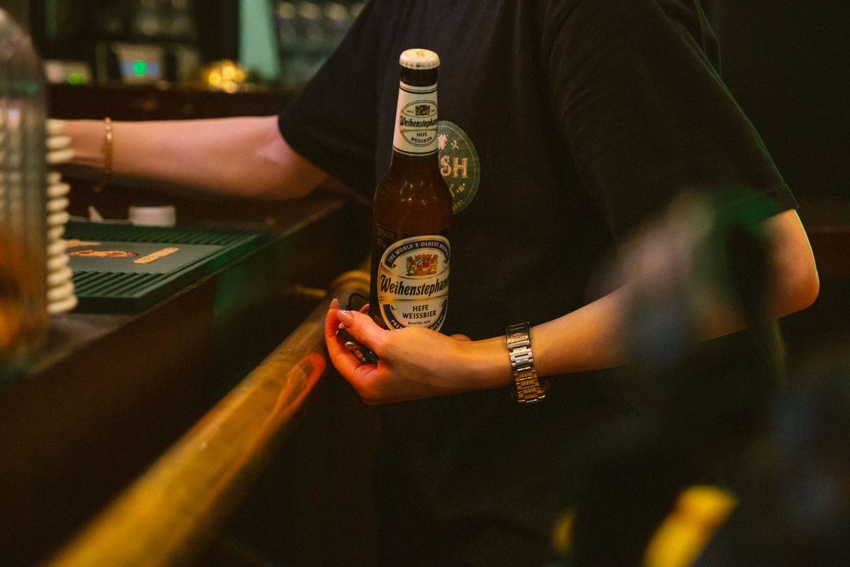 A bartender holds a bottle of Weihenstephaner Hefe Weissbier, the brewery's signature wheat beer.