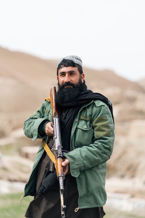 Free Portrait of an Afghan man holding a rifle in a rural landscape, depicting life in Afghanistan. Stock Photo