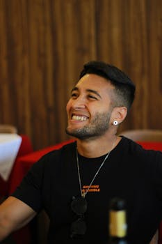 A cheerful man in a cozy restaurant setting, exuding joy and relaxation.