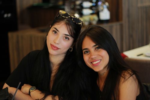 Free Two young women enjoying a relaxed moment indoors at a stylish restaurant in Braga, Portugal. Stock Photo