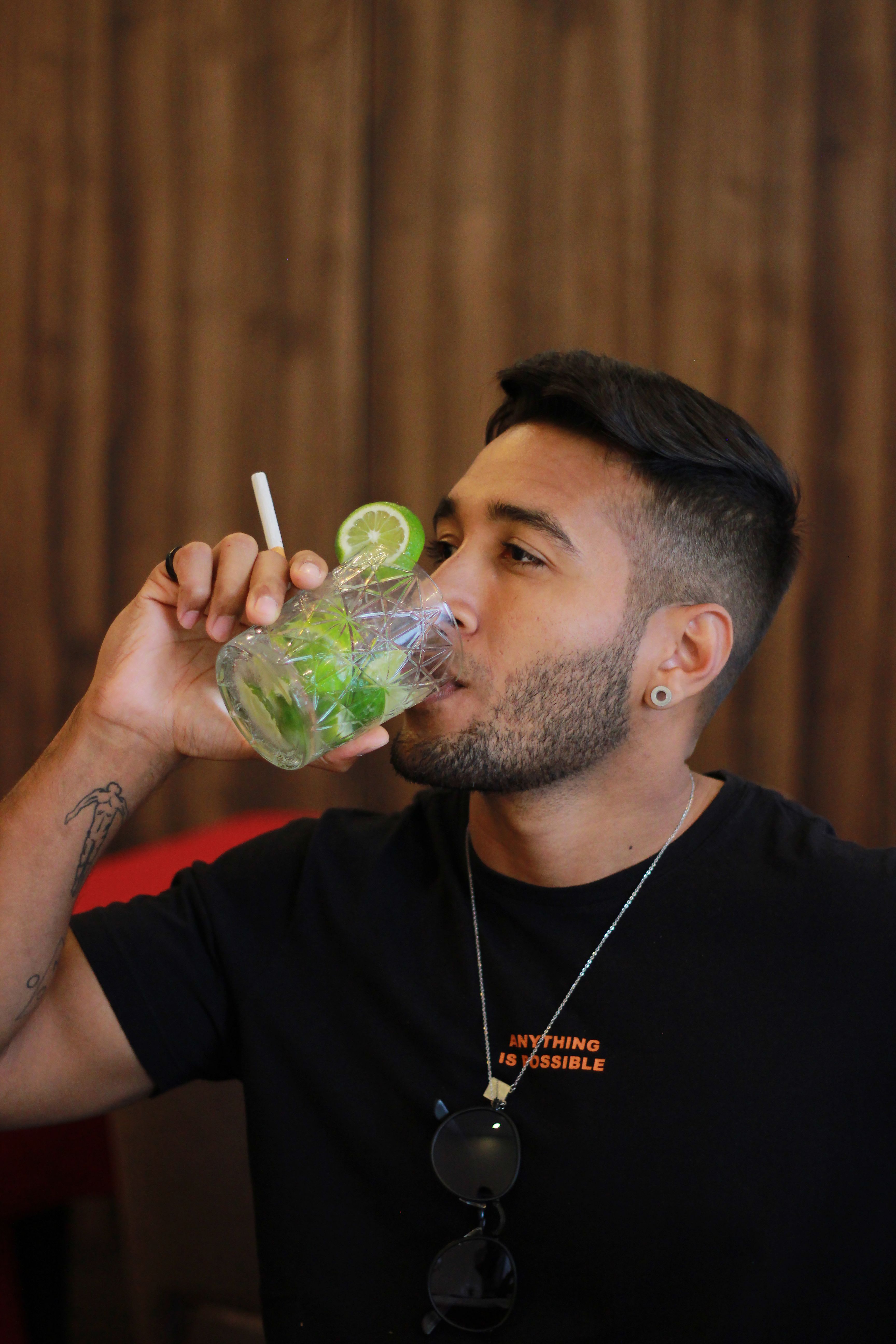A young man enjoys a refreshing mojito in a stylish restaurant setting.