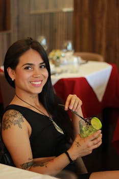 Smiling woman with tattoos enjoying a cocktail at a Braga restaurant.