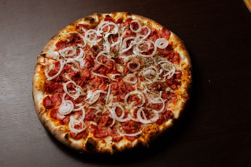 Free A mouth-watering pepperoni pizza topped with sliced onions on a dark wooden table. Stock Photo