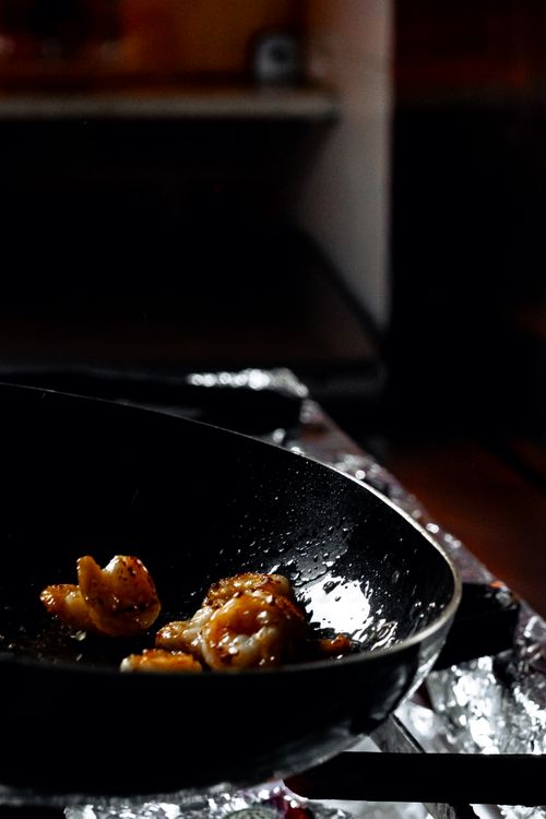 Free Close-up of shrimp cooking in a black frying pan on a stove, dark kitchen. Stock Photo
