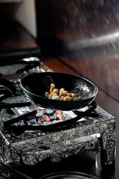 Sizzling food being cooked on a stove in a frying pan captured indoors.