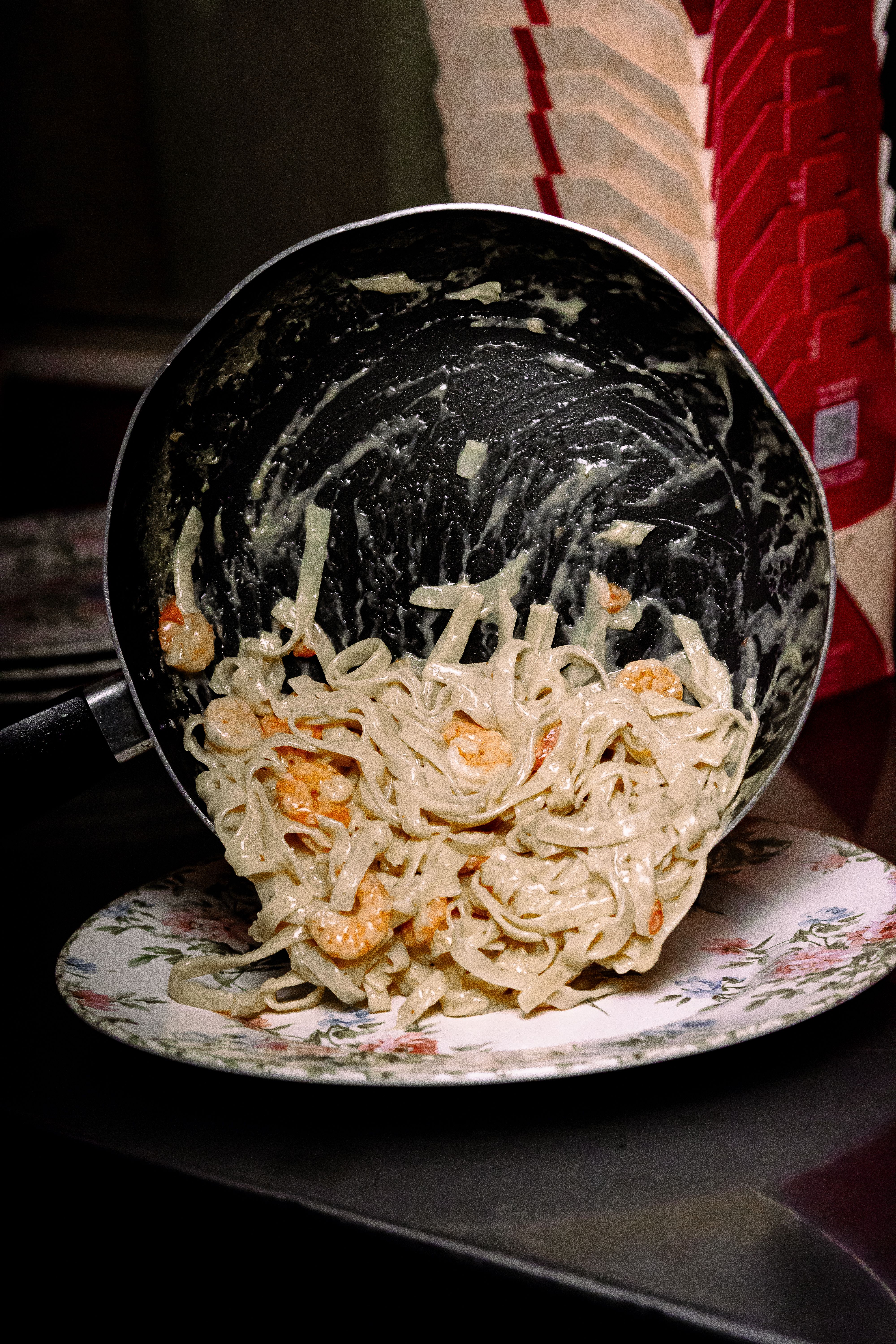 Delicious creamy shrimp pasta being served onto a decorative plate from a pan.