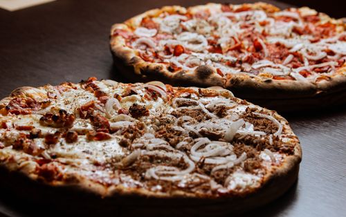 Free Close-up of two mouth-watering pizzas topped with onions, captured indoors. Stock Photo