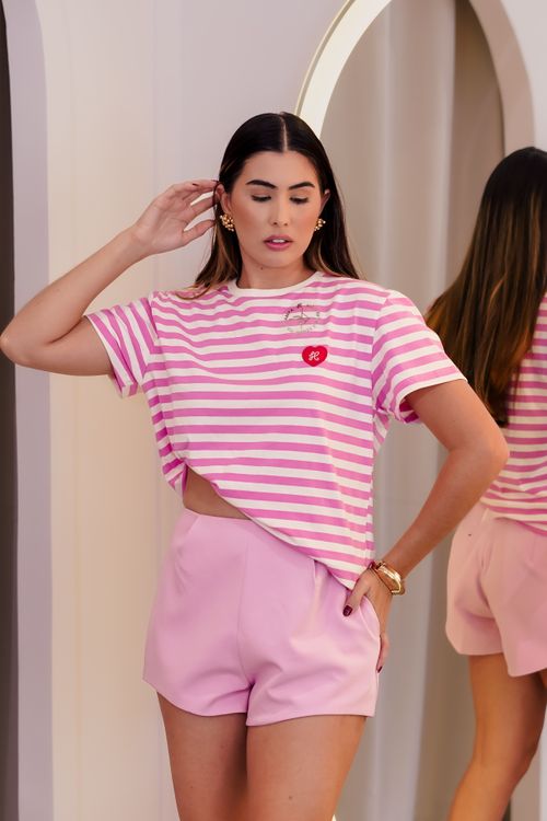 Free Stylish woman in pink striped T-shirt and shorts posing indoors by a mirror. Stock Photo