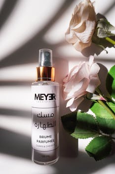 Elegant perfume bottle placed beside delicate roses with soft shadow play.