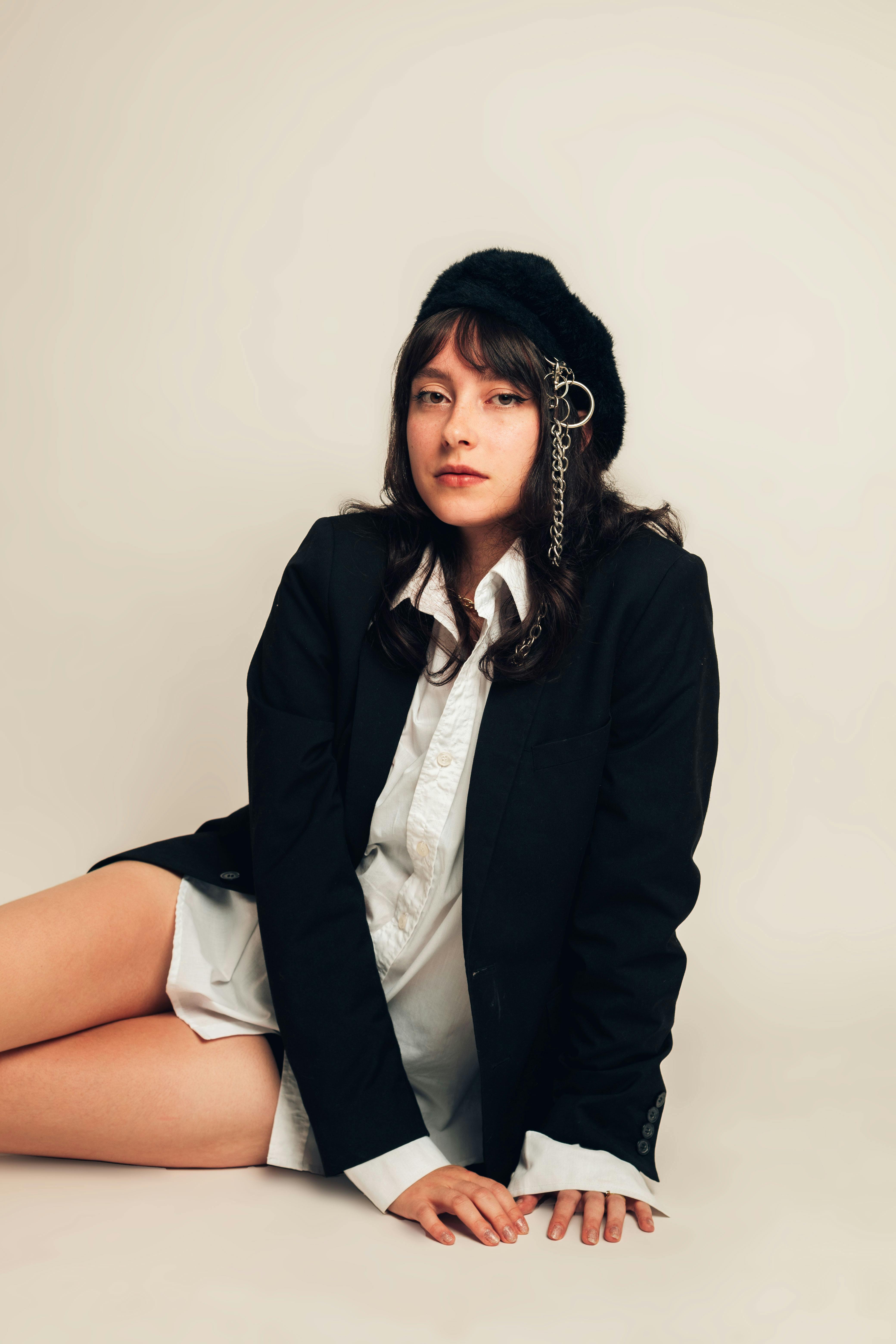 Young woman in a black beret and blazer sitting against a plain background.