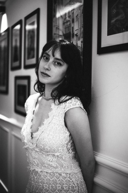 Free A timeless black and white portrait of a woman in a lace dress, leaning against a wall. Stock Photo